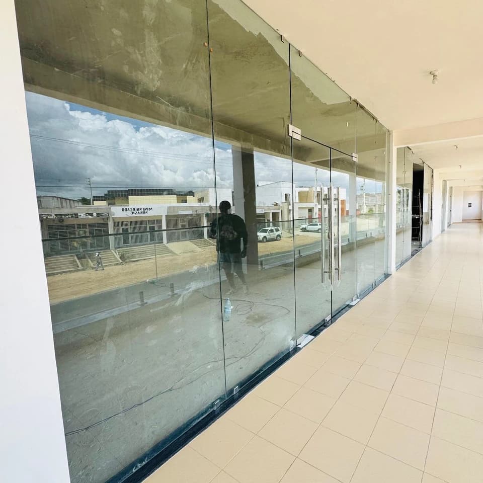 Fachada envidraçada de pé-direito completo num corredor comercial.