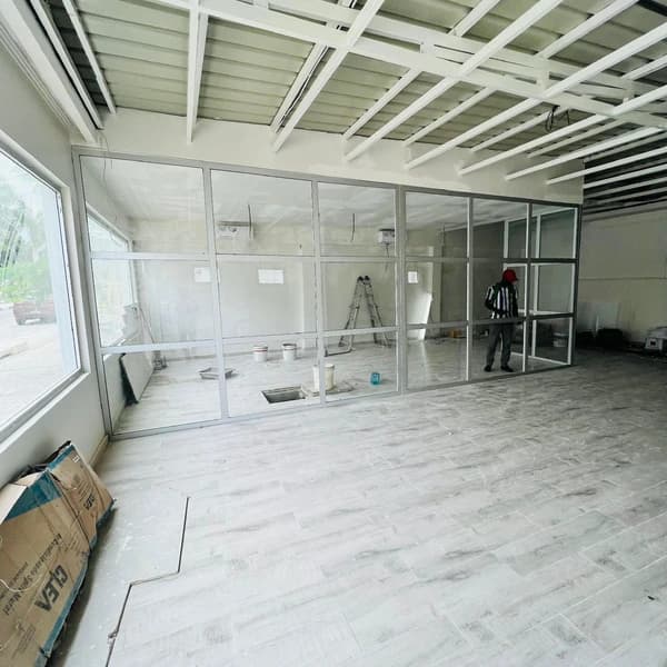 Divisórias envidraçadas a separar salas num espaço comercial em acabamento.
